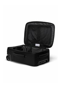 Valise à roulettes noire à parois souples avec couvercle ouvert montrant une poche en filet et un intérieur vide, sur fond blanc.