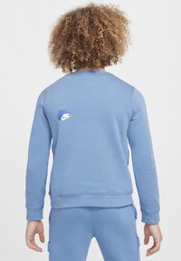 Sudadera azul hecha de material suave, con cuello redondo, mangas largas y un pequeño logotipo blanco de Nike con acentos azules en la parte posterior.