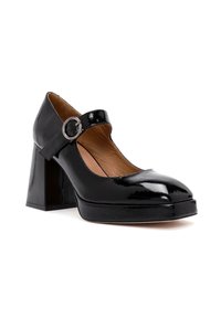 Chaussure Mary Jane en cuir verni noir avec boucle ronde en argent, talon bloc, et doublure intérieure en cuir tanné clair.