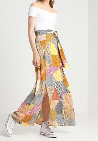 Gonna maxi con un design a patchwork in arancione, giallo, rosa e motivi floreali neri. Realizzata in tessuto leggero con cintura regolabile.