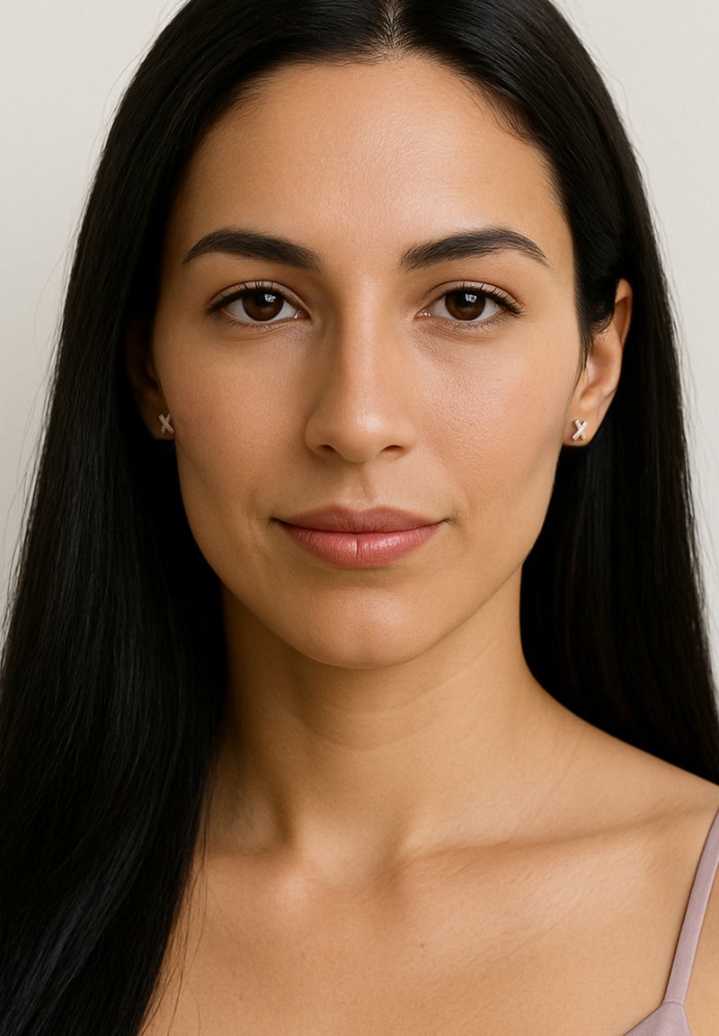 Silver studs i form av ett "X", buren av en person med långt, rakt mörkt hår och en neutral bakgrund. Slät hudtextur.