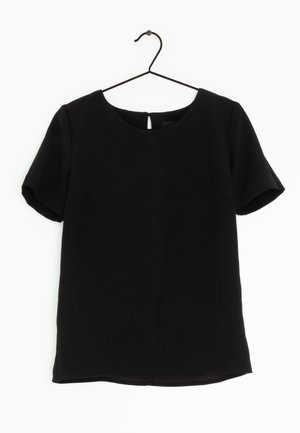 Blusa nera a maniche corte con scollatura tonda appesa a una gruccia in metallo nero su uno sfondo bianco.