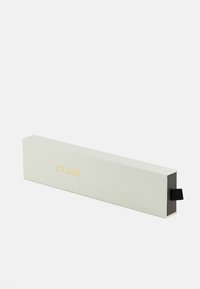 Emballage rectangulaire, vert clair avec une surface texturée. Logo "CLUSE" doré à l'avant. Comprend une languette noire pour l'ouverture.