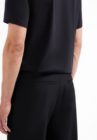 Zwarte short-sleeve shirt, gecombineerd met zwarte broeken, met een slank ontwerp, gladde textuur en minimalistische achterzakdetails.