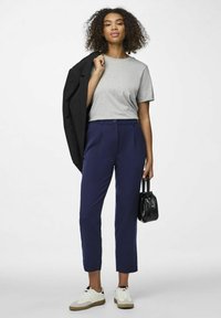 Pelēks kokvilnas T-krekls, zili pielāgoti bikses, melna žakete, kas uzlikta uz pleca, melna rokassoma, baltas un pelēkas čības.