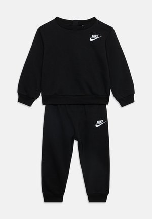 Czarny zestaw z bluzą z długim rękawem i spodniami z prążkowanymi mankietami, z białymi logo Nike na piersi i lewym udzie.