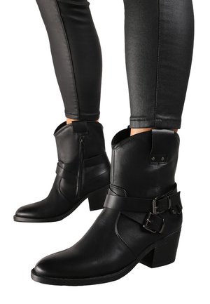 Bottines en cuir noir avec un talon épais, détail de sangle à boucle et fermeture éclair sur le côté. Fini texturé avec un design à bout pointu.