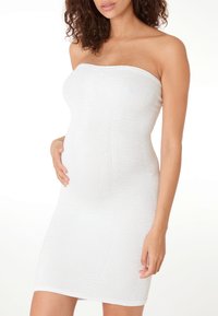 Weißes trägerloses Kleid aus strukturiertem Stoff mit geripptem Design. Körpernahe Silhouette, knielang, mit einem glatten, elastischen Finish.