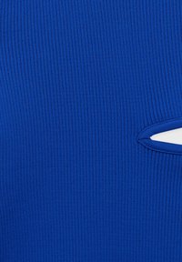 Tissu bleu côtelé avec un détail découpé. La texture est lisse, avec des lignes verticales créant une apparence structurée.