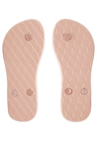 Lichtroze rubberen schoenzolen hebben een gestructureerd oppervlak met diamantpatronen en ronde inlegstukken nabij de middenzool en hiel.