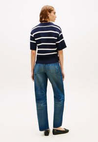 Μπλε σκούρο και λευκό ριγέ κοντομάνικο πουλόβερ συνδυασμένο με τζιν μεσαίας μέσης σε μπλε χρώμα και μαύρα μπαλαρίνια, με άνετη εφαρμογή και μαλακή υφή.