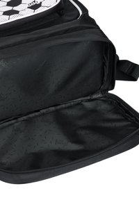 Interno di uno zaino nero con una texture liscia e solida, caratterizzato da un motivo con logo e senza scomparti. Chiusura con cerniera e cuciture rinforzate.