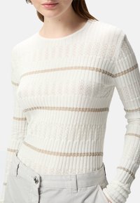 Top a maniche lunghe rigato avorio con strisce orizzontali color nocciola e motivi texturizzati. Presenta un collo rotondo e una silhouette aderente.