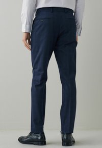 Námořnické kostkované kalhoty s elegantním designem, slim fit a jemnou strukturou. Mají zadní kapsy a jsou kombinovány s černými společenskými botami.