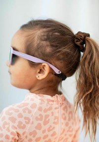 Violet sunglasses with green lenses, worn by a child with a brown scrunchie, are matched with a pink leopard patterned suit.