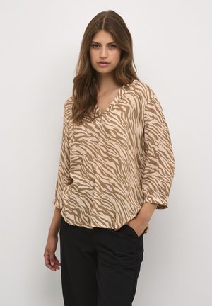 Beige und hellbraun gestreifte Bluse mit V-Ausschnitt, dreiviertel Ärmeln und lockerer Passform, kombiniert mit schwarzen Hosen.