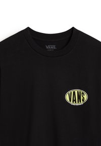 Camiseta negra de corte holgado hecha de algodón, con un logo ovalado amarillo que tiene el texto "VANS" en el pecho. Cuello redondo y mangas cortas.