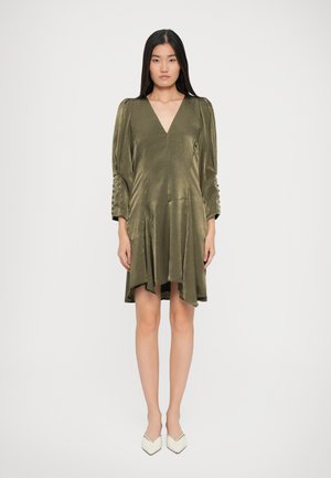 Rochie verde măslinie cu decolteu în V, mâneci lungi cu bufant și accente cu nasturi pe mansete; design fluid cu o croială asimetrică.