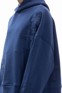 Granatowa, oversize'owa bluza z kapturem wykonana z miękkiego materiału, z teksturowanymi haftowanymi wzorami krzyży na przodzie oraz kieszenią kangurką.