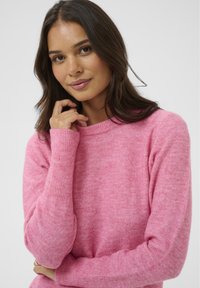 Fukšijas rozā džemperis, izgatavots no mīkstas dzijas, ar apaļu kakla izgriezumu un ribinātām piedurknēm, atvieglināts piegriezums un gluda tekstūra.