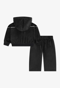 Sort velour træningsdragt med en hættejakke med hvide detaljer og matchende bukser med elastisk liv. Blød tekstur overalt.
