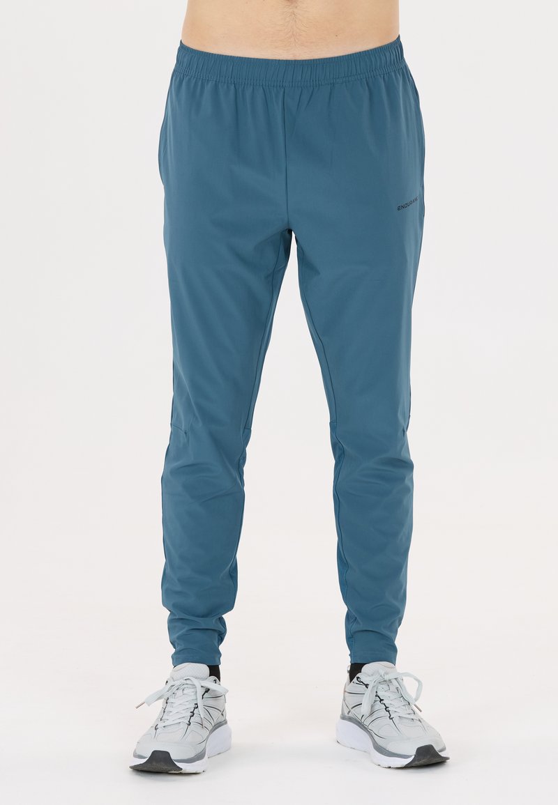 Teal löparbyxor med elastisk midja, avsmalnande passform och ventilerande tyg. Har minimal branding och en mjuk textur.