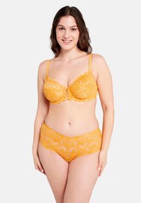 Reggiseno giallo in pizzo con slip a vita alta coordinati. Motivo floreale, bordo scalloped e spalline regolabili sul reggiseno. Texture morbida.