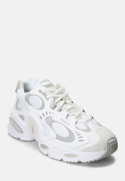 White athletic sneaker featuring textured mesh and suede panels, reflective accents, and cushioned sole. Embossed "POLO" branding on sides.