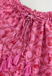 Tissu rose avec motifs de homard rouge et fleurs, avec une ceinture froncée, un cordon noué et quatre pompons roses.