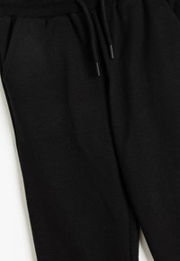 Schwarze Baumwoll-Sweatpants mit weicher Textur, ausgestattet mit einem elastischen Bund, Kordelzug und seitlichen Taschen. Glattes und vielseitiges Design.