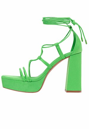 Green suede platform sandals with a thick, square heel and multiple strap designs. Features ankle ties for a secure fit.