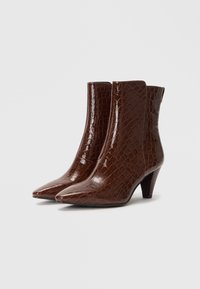 Brown, crocodile-textured ankle boots with a pointed toe and a modest heel. Smooth, shiny finish with a sleek design.