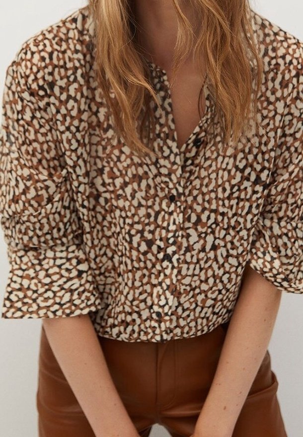 Chemise à boutons marron et crème avec un motif léopard, tissu léger, manches trois-quarts, associée à un pantalon en cuir marron.