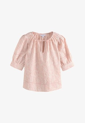 Heleroosa tikanditega pluus, millel on õhupuhuvad kolmekvartvarrukad, ümmargune kaelus ja nöördetail ees võtmeaugul.