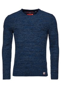 Pull en tricot bleu marine à manches longues, encolure arrondie, et tissu texturé. Petite étiquette logo rouge sur le côté inférieur gauche.