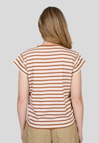 T-shirt à rayures avec des manches courtes, présentant des rayures alternées marron clair et crème, un col rond et une texture de tissu douce.