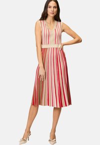 Sleeveless V-neck dress featuring vertical red, beige, and pink stripes, with a fitted waist and flared skirt. Soft knit texture.