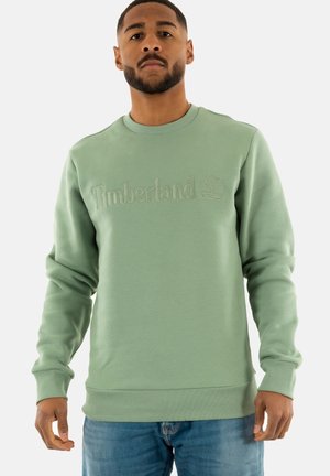Felpa verde con logo Timberland testurizzato, colletto a girocollo e polsini e orlo a costine. Realizzata in tessuto morbido con un fit classico.