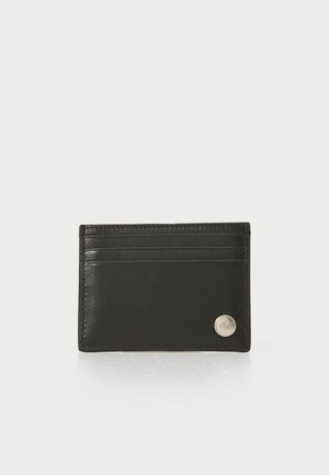 Porte-cartes en cuir noir avec quatre emplacements pour cartes, texture lisse et un accent métallique dans le coin inférieur droit. Forme rectangulaire compacte.