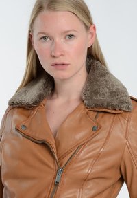 Brun læder motorcykeljakke med en faux fur krave, der har skrå lynlåse og knapdetaljer, glat tekstur og tætsiddende design.