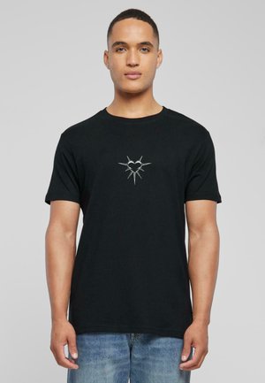 Black cotton t-shirt featuring a central silver heart design with radiating spikes. Regular fit, short sleeves, and crew neck style.