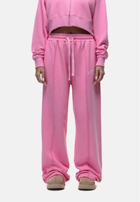 Roze sweatshirt met een cropped ontwerp en rits aan de voorkant, gecombineerd met losse roze sweatpants met een drawstring taille en zijnaadstiksels.