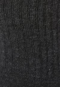Tessuto nero lavorato a maglia con un motivo testurizzato, con fibre sottili che creano un aspetto morbido e una leggera lucentezza. Colore uniforme in tutta la superficie.