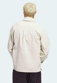 Chaqueta de pana en beige claro con cuello, mangas largas y detalle de canesú en la espalda. Diseñada con un ajuste relajado y una textura sutil.