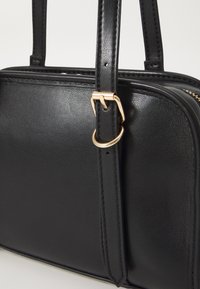 Borsa a tracolla in pelle nera con una finitura liscia, caratterizzata da accessori in tonalità oro, manici robusti e una chiusura con cerniera.
