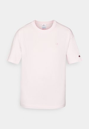 Lys rosa bomull t-skjorte med korte ermer, rund hals og en liten brodert logo på brystet og ermet. Glatt tekstur.