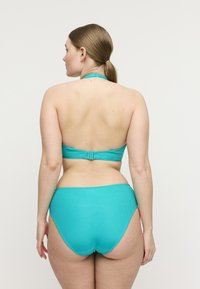 Set bikini turchese a coste con design a collo allacciato; chiusura posteriore regolabile e slip a vita alta con dettagli di cuciture intricate.