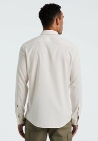 Lichtbeige langemouw shirt met een button-down kraag, gestructureerde stof en zijsplitsingen aan de manchetten. Getailleerde pasvorm met een ronde zoom.