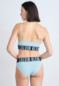 Lichtblauw bikini set met een bralette met dunne bandjes en een hoog uitgesneden onderstuk, beide met een zwarte Calvin Klein logo band.