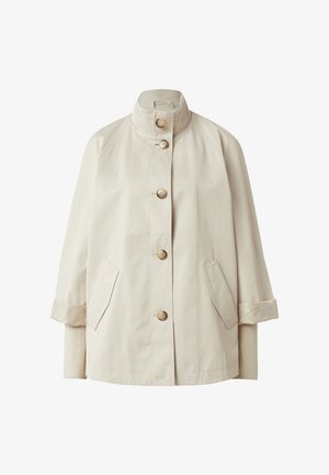 Beige knopfbare Jacke mit Stehkragen, zwei Fronttaschen und gestrickten Bündchen, die von hochgekrempelten Ärmeln hervorstehen.